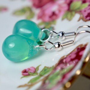 May include: A pair of silver teardrop earrings with light green glass drops.