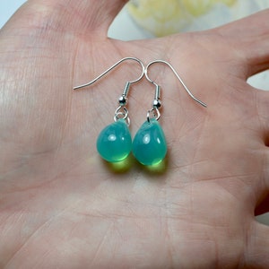 May include: A pair of silver teardrop earrings with light green glass drops.