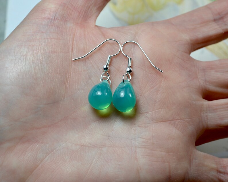 May include: A pair of silver teardrop earrings with light green glass drops.