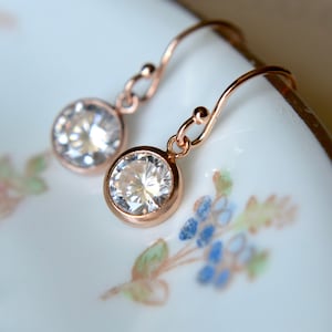 Puede incluir: Un par de pendientes colgantes de oro rosa con piedras redondas de circonita c&uacute;bica transparentes.