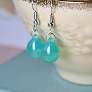 May include: A pair of silver teardrop earrings with light blue gemstone drops.