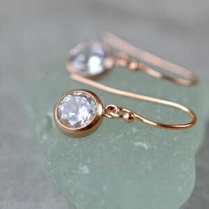 Puede incluir: Un par de pendientes de oro rosa con una piedra redonda transparente. Los pendientes tienen un dise&ntilde;o simple y elegante, perfectos para el uso diario.