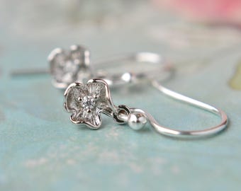 Pequeños pendientes de flores de plata con ganchos de plata de ley. Gotas delicadas con circonitas. Joyas florales para orejas perforadas.