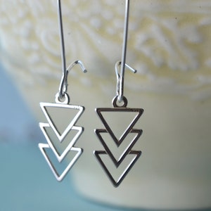 May include: Silver dangle earrings with a geometric design of three stacked triangles.