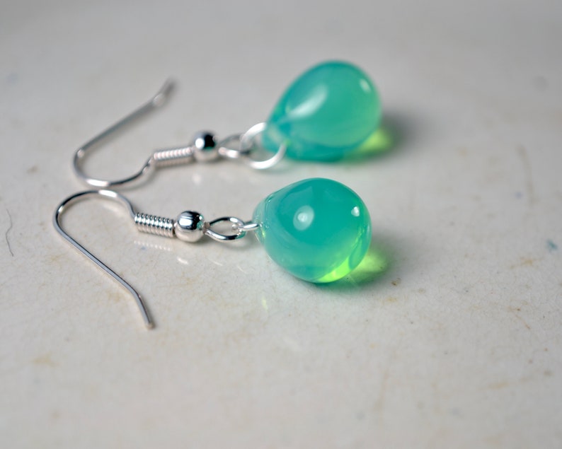 May include: A pair of silver teardrop earrings with light blue glass teardrop beads.
