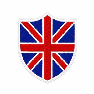 Può includere: Una toppa ricamata a forma di scudo con il design della bandiera Union Jack. La toppa presenta una croce rossa centrale e strisce diagonali rosse su sfondo blu, il tutto delineato da un bordo bianco spesso e dettagli di cucitura bianchi.