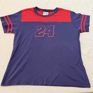 May include: A short-sleeve t-shirt featuring a dark blue body with a red horizontal panel across the chest and shoulders. The number 24 is printed in red on the front. The sleeves have two red stripes, and the collar is trimmed in red.