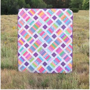 May include: A quilt pattern titled The Iris Quilt by Erica Jackman from Kitchen Table Quilting. The quilt features a geometric design with diagonal strips of multi-colored fabric in pink, orange, green, and blue, separated by purple squares.