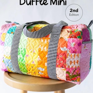 May include: A quilted duffle bag featuring a colorful patchwork design with various patterns and motifs. The bag has black and white striped handles and the text Patchwork Duffle Mini 2nd Edition and KNOT + THREAD design visible in the image.