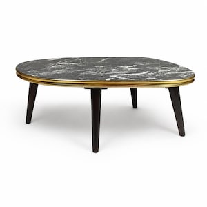 Può includere: Un tavolino da caffè con piano ovale caratterizzato da un motivo in marmo bianco e nero. Il piano è rifinito con un sottile bordo in metallo dorato. Il tavolo è sostenuto da quattro gambe in legno marrone scuro, affusolate e leggermente inclinate.