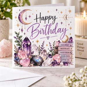 May include: A square greeting card with the text Happy Birthday in purple script. The design features illustrations of purple and pink crystals, lavender sprigs, a crescent moon, and a stack of books labelled Good Energy, Brighter Days, Bigger Dreams, Kinder People, and Happier You.