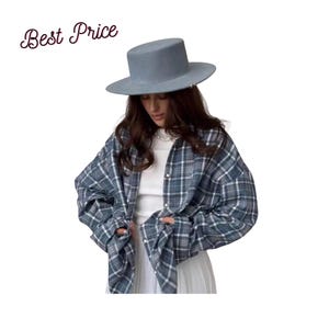 Könnte beinhalten: Ein hellblauer Hut mit flacher Krempe und ein blau-weiß kariertes Hemd über einem weißen Oberteil. Der Text "Best Price" ist in der oberen linken Ecke sichtbar. Das Outfit umfasst einen weißen Faltenrock und eine weiße Perlenkette.