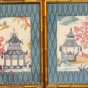 May include: A pair of framed wall art pieces featuring gold bamboo-style frames and blue patterned matting. The central fabric panels display illustrations of pagodas, trees with pink leaves, and a small bridge on a cream-colored background.