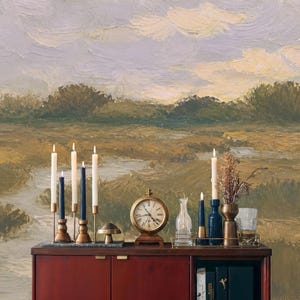 May include: A dark red wooden cabinet topped with five white candles in brass holders, two dark blue candles in brass holders, a small brass mushroom, a round brass clock, a glass vase with dried flowers, and a glass tumbler.