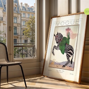 May include: A framed vintage Vogue magazine cover print featuring an illustration of a person in a green coat and wide-brimmed hat riding a zebra. The artwork includes the text VOGUE at the top and smaller text at the bottom, set against a light background.