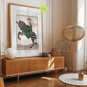 May include: A framed Vogue magazine cover art print featuring an illustration of a person in a green coat and pink hat riding a zebra. The print includes the text VOGUE at the top and a small green circular label in the corner that says DIGITAL.