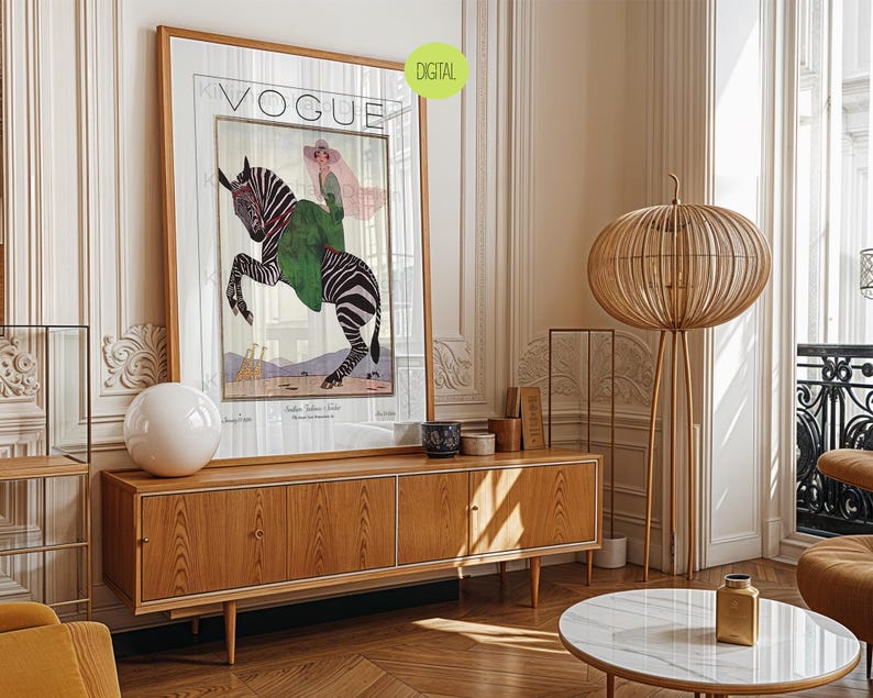 May include: A framed Vogue magazine cover art print featuring an illustration of a person in a green coat and pink hat riding a zebra. The print includes the text VOGUE at the top and a small green circular label in the corner that says DIGITAL.