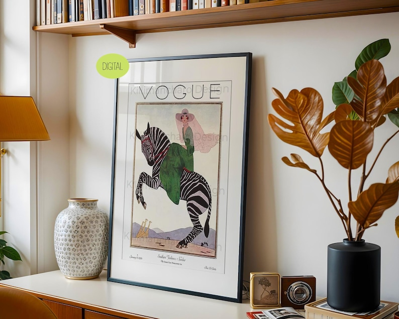 May include: A framed wall art print featuring a vintage Vogue magazine cover illustration. The artwork depicts a person in a green coat and pink hat riding a rearing zebra, with two giraffes in the background. The text VOGUE is printed at the top.