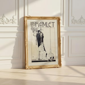 Op de afbeelding: Een ingelijste kunstdruk getiteld HAMLET met een zwart-witillustratie van een figuur in een mantel die een zwaard vasthoudt achter een zittend persoon, met een schedel op de grond. De sierlijke gouden lijst heeft gedetailleerde bloemmotieven.