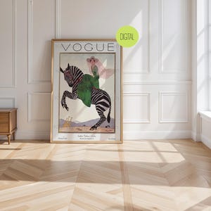 May include: A framed Vogue magazine cover print featuring an illustration of a person in a pink hat and green coat riding a zebra. The artwork includes the text VOGUE at the top and smaller text at the bottom, with a green circular DIGITAL label.