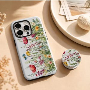 May include: A white smartphone case and a matching circular phone grip, both featuring a detailed watercolour-style print of various wildflowers in shades of red, yellow, pink, and green, arranged in a vertical botanical pattern across the surfaces.
