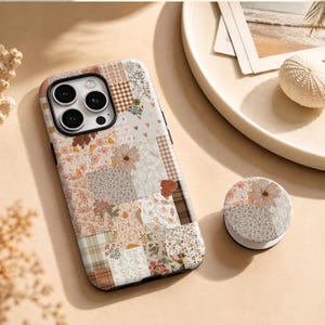 May include: A smartphone case and a matching circular phone grip featuring a patchwork design of various patterns including brown gingham, floral prints, small hearts, and botanical illustrations in shades of beige, cream, and muted brown tones.