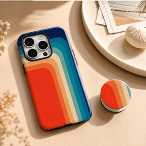May include: A smartphone case and a matching circular phone grip featuring a pattern of vertical, curved stripes in shades of red, orange, cream, teal, and dark blue. The case has a cutout for a triple-lens camera system on the back.