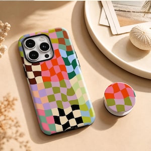 May include: A smartphone case and a matching circular phone grip featuring a distorted, wavy checkerboard pattern in vibrant colors including orange, pink, green, light blue, lavender, black, and brown, with a black camera lens cutout.