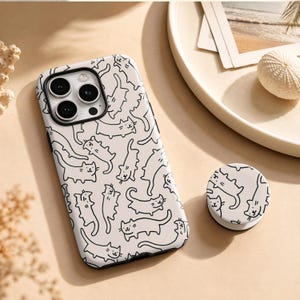 May include: A white smartphone case and a matching circular phone grip, both featuring a repeating pattern of simple black line-drawn cats. The case has a cutout for a triple-lens camera system, and the phone grip is a round, collapsible accessory.