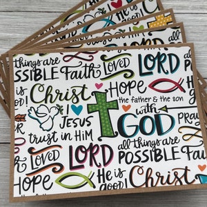 May include: A stack of blank greeting cards with a brown kraft paper border. The cards feature a white background with colorful text and illustrations. The text includes words like "Christ", "Hope", "Lord", "Jesus", "God", and "Possible".