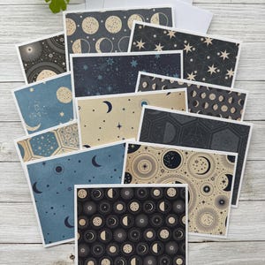 May include: A set of 12 cards featuring different moon and star patterns. The cards are printed on textured paper with a vintage aesthetic. The patterns include moons in various phases, stars, and geometric shapes. The cards are in shades of blue, black, and cream.