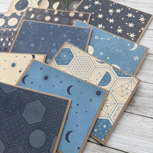 May include: A set of ten cards featuring different celestial patterns. The cards are blue, cream, and black with various moon phases, stars, and geometric designs.