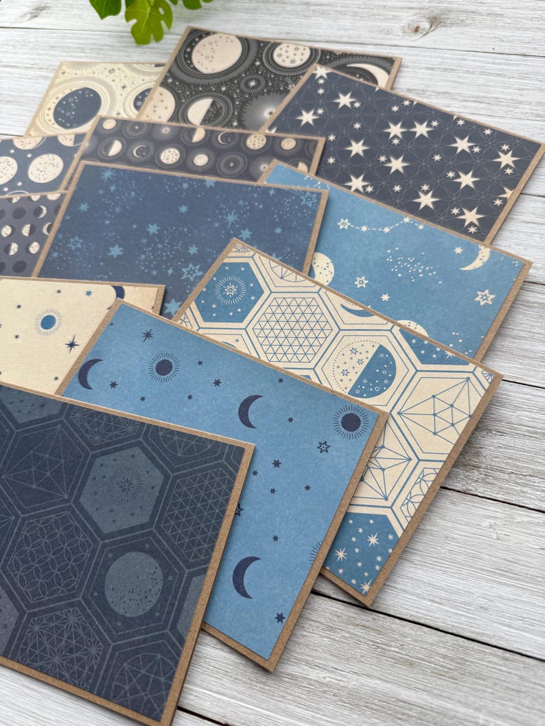May include: A set of ten cards featuring different celestial patterns. The cards are blue, cream, and black with various moon phases, stars, and geometric designs.