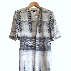 Peut inclure: Une longue veste à imprimé serpent blanc et noir avec une ceinture. L'étiquette indique "Albert Nipon".