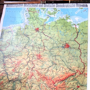 May include: A vintage map of Germany and East Germany, featuring detailed geographical information. The map is printed on aged paper, with text in German at the top. The map shows cities, rivers, and political boundaries in various colors.