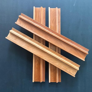 Peut inclure: Quatre &eacute;tag&egrave;res en bois longues et rectangulaires avec une finition en grain de bois brun clair naturel. Chaque &eacute;tag&egrave;re pr&eacute;sente un bord sur&eacute;lev&eacute; sur un c&ocirc;t&eacute;, cr&eacute;ant un canal ou un rebord &eacute;troit. Les &eacute;tag&egrave;res sont dispos&eacute;es en croix, se chevauchant.