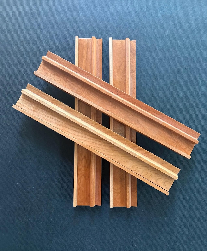 Peut inclure: Quatre &eacute;tag&egrave;res en bois longues et rectangulaires avec une finition en grain de bois brun clair naturel. Chaque &eacute;tag&egrave;re pr&eacute;sente un bord sur&eacute;lev&eacute; sur un c&ocirc;t&eacute;, cr&eacute;ant un canal ou un rebord &eacute;troit. Les &eacute;tag&egrave;res sont dispos&eacute;es en croix, se chevauchant.