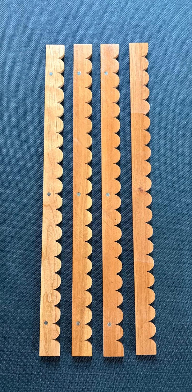 Peut inclure: Quatre longues bandes de bois &eacute;troites avec un bord festonn&eacute; sur un c&ocirc;t&eacute;. Chaque bande pr&eacute;sente une finition en grain de bois brun clair et comprend trois petites attaches m&eacute;talliques circulaires ou trous de vis espac&eacute;s r&eacute;guli&egrave;rement.