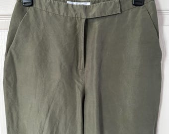 May include: Olive green trousers hanging on a black hanger. The pants have a straight leg design with side pockets and a front closure. The fabric has a slight sheen, and the pants appear to be made of a lightweight material.
