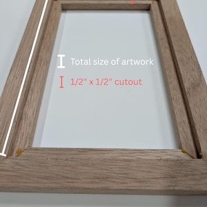 以下が含まれることがあります： 内側の縁に1.27cm x 1.27cmの切り込みがある、明るい茶色の木製長方形フレーム。フレームには、アートワークの合計サイズと内側の切り込み部分の具体的な寸法を示す白いグラフィックラインが含まれています。