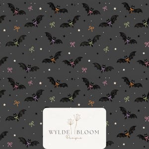 May include: A dark gray fabric pattern featuring repeating black bats with small bows in orange, pink, and light green, interspersed with white and black stars. A white rectangular label at the bottom displays the text WYLDE BLOOM Designs.