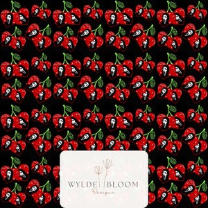 May include: A repeating pattern on a black background featuring red cherries where each cherry is shaped like a heart and displays the white Ghostface mask from the Scream horror movie franchise. A white rectangular logo reads WYLDE BLOOM Designs.