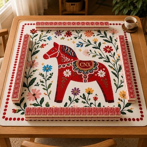 Peut inclure: Un tapis de mah-jong carré à fond blanc orné d'une illustration centrale de cheval de Dalécarlie rouge portant les lettres CNX. Le tapis présente des motifs floraux colorés et une bordure à pois rouges, entouré de quatre rangées de tuiles rouges.