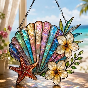 May include: A stained glass suncatcher featuring a large iridescent seashell in shades of blue, pink, and gold. The piece includes a textured red starfish, two white tropical flowers with yellow centers, and green leaves, all suspended by a black chain.