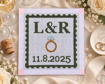 Op de afbeelding: Een vierkant borduurcanvas met een donkergroene geschulpte rand, de letters L & R, een gouden verlovingsring-icoon met een lichtblauwe diamant en de datum 11.8.2025 in donkergroen op een witte rasterachtergrond.