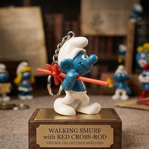 Può includere: Un portachiavi Puffo raffigurante un personaggio blu con cappello e pantaloni bianchi, che trasporta un bastone rosso a forma di croce. La figura è montata su una base rettangolare in legno con una placca dorata che recita: WALKING SMURF with RED CROSS-ROD VINTAGE COLLECTIBLE KEYCHAIN.