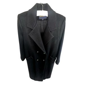 May include: A black double-breasted coat featuring a wide notched lapel, long sleeves, and two front pockets. The garment includes a dark interior lining and a Pendleton brand label located at the inner neckline, hanging on a white hanger.