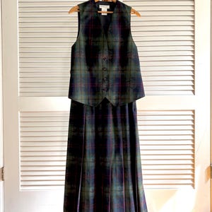 May include: A sleeveless vest and a matching pleated midi skirt set featuring a dark green, navy blue, and burgundy plaid tartan pattern. The vest has a V-neckline with four front buttons and a Pendleton brand label visible at the inner collar.