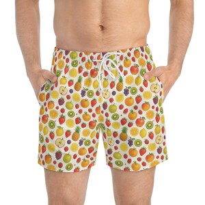 Può includere: Costume da bagno bianco con una stampa di frutta colorata su tutta la superficie, inclusi fragole, ananas, arance, limoni, kiwi, mele e uva. Il pantaloncino presenta una vita elastica con una coulisse bianca per una vestibilità regolabile.