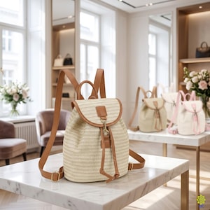 May include: A beige woven straw backpack featuring tan faux leather trim, a top handle, adjustable shoulder straps, and a front flap closure secured with a gold-toned metal clasp and a drawstring cord. The bag has a structured, rounded base.
